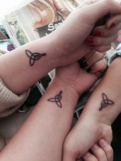 two girls with matching tattoos on their arms holding each other's hands and looking at the camera