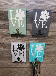 three wall hooks with dog paw prints and love written in white, black, and blue