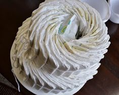 a ball of white yarn sitting on top of a wooden table next to two cups