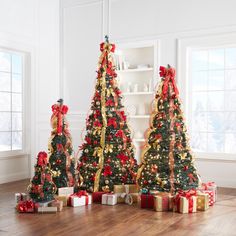 three christmas trees decorated with red and gold ribbons, wrapped in golden ribbon bowes