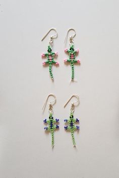 three pairs of beaded cactus earrings on a white table with scissors and thread spools