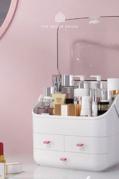 a white box filled with lots of different types of cosmetics and other items next to a mirror