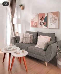 a living room with grey couches and pink pillows on top of the sofas