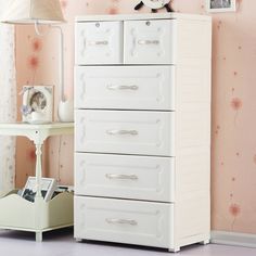 a white dresser sitting next to a pink wall