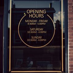 an open hours sign in the window of a building