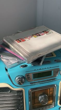 an old blue radio with cd's stacked on top of each other in front of a white wall