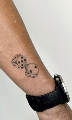 a man's arm with two dice tattoos on it