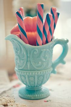 some pink and blue striped candles in a teal cup