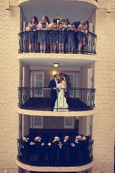 a bride and groom standing on the balcony of a building