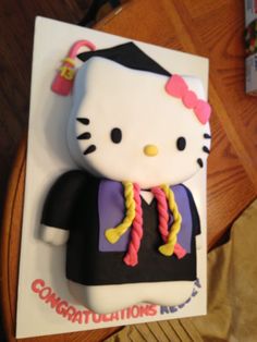 a hello kitty graduation cake on top of a table