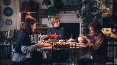 three women sitting around a table with food on it