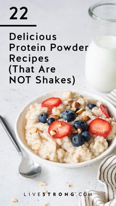 a bowl of oatmeal with strawberries and blueberries next to a glass of milk