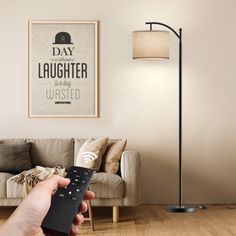 a person holding a remote control in front of a couch with a poster on the wall