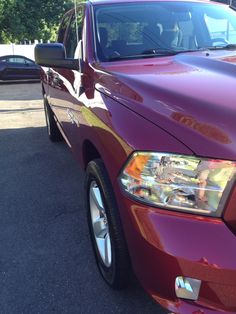 the front end of a red truck parked in a parking lot next to other cars