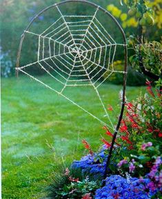 a spider web in the middle of a flower garden with blue and red flowers around it