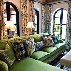 a living room filled with green couches and lots of pillows on top of them