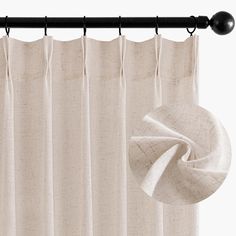 a white curtain hanging on a black rod with an unrolled piece of fabric next to it