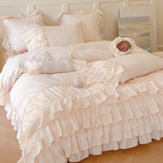 a white bed with ruffled sheets and pillows