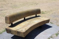 a wooden bench sitting on top of a cement slab in a park next to grass