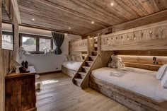 two beds in a room with wooden walls and stairs leading up to the second floor