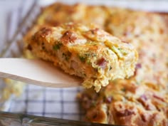 a close up of food on a wooden spoon in a casserole dish with broccoli and cheese