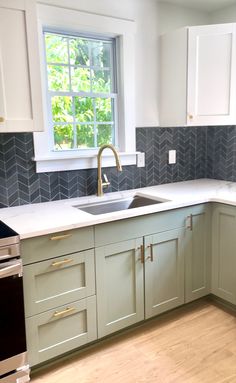 an empty kitchen with white cabinets and gray tile backsplash, wood flooring