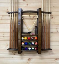 a rack with pool balls and cues in it on the wall next to a wood paneled wall