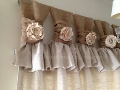 the curtains are lined up with ruffles and flower decorations on top of them