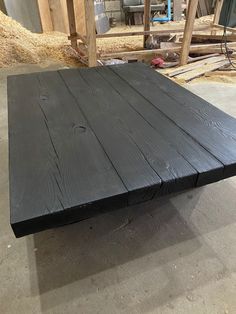 a wooden table sitting in the middle of a room next to some wood planks