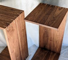 two wooden stools sitting next to each other on a white sheeted surface,