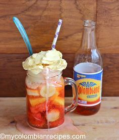 a mason jar filled with fruit and ice cream sitting on top of a wooden table