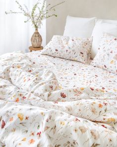 an unmade bed with white linens and flowers on the comforter is shown