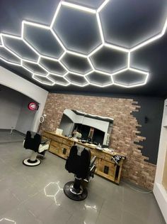 a room with some chairs and lights on the ceiling in front of a brick wall