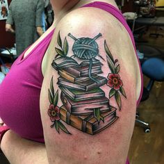 a woman with a tattoo on her arm is holding a stack of books