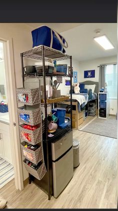 this is a dorm room with a bed, desk and storage bins on the floor