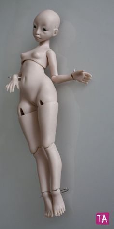 a white mannequin with no shirt on leaning against a wall