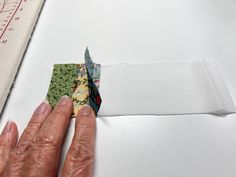 someone is cutting fabric with scissors on top of a piece of paper that has been sewn together