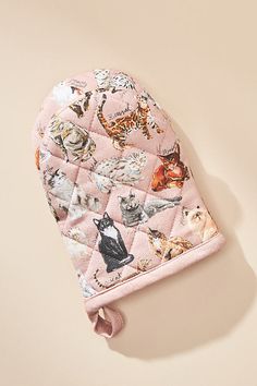 a pink oven mitt with cats all over it on top of a beige background