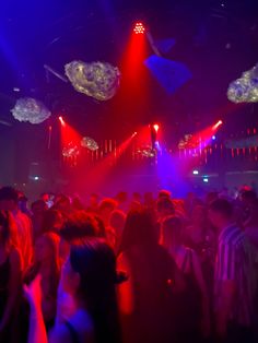 a large group of people are dancing at a party with bright lights on the ceiling