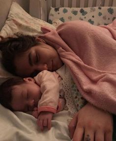 two young children sleeping in a crib with their hands on each other's heads