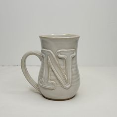 a white ceramic mug with the letter n on it