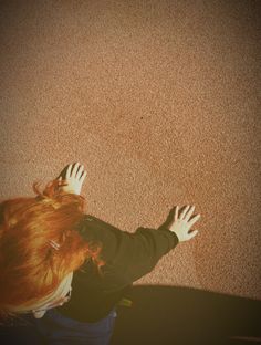 a woman with red hair reaching up into the air