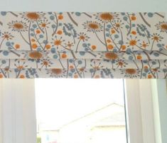 the window is decorated with flowers and blue, orange, and white colors on it's valance