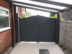 an open gate in front of a brick building with a metal grate on the ground