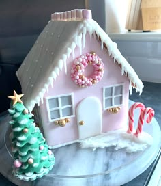 a pink gingerbread house decorated with candy canes and candies on a plate