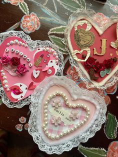 three heart shaped valentine's day decorations on a table with lace doily and flowers