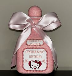 a pink bottle with a hello kitty label on it's side and a bow around the neck