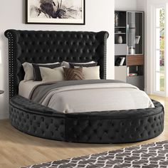 a large bed with black headboard and foot board in a white walled bedroom area