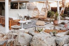 a patio with rocks and plants in the foreground, covered by a pergolated roof