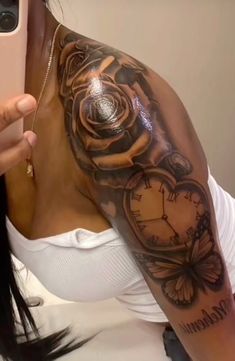 a woman taking a selfie with her cell phone and clock tattoo on her arm